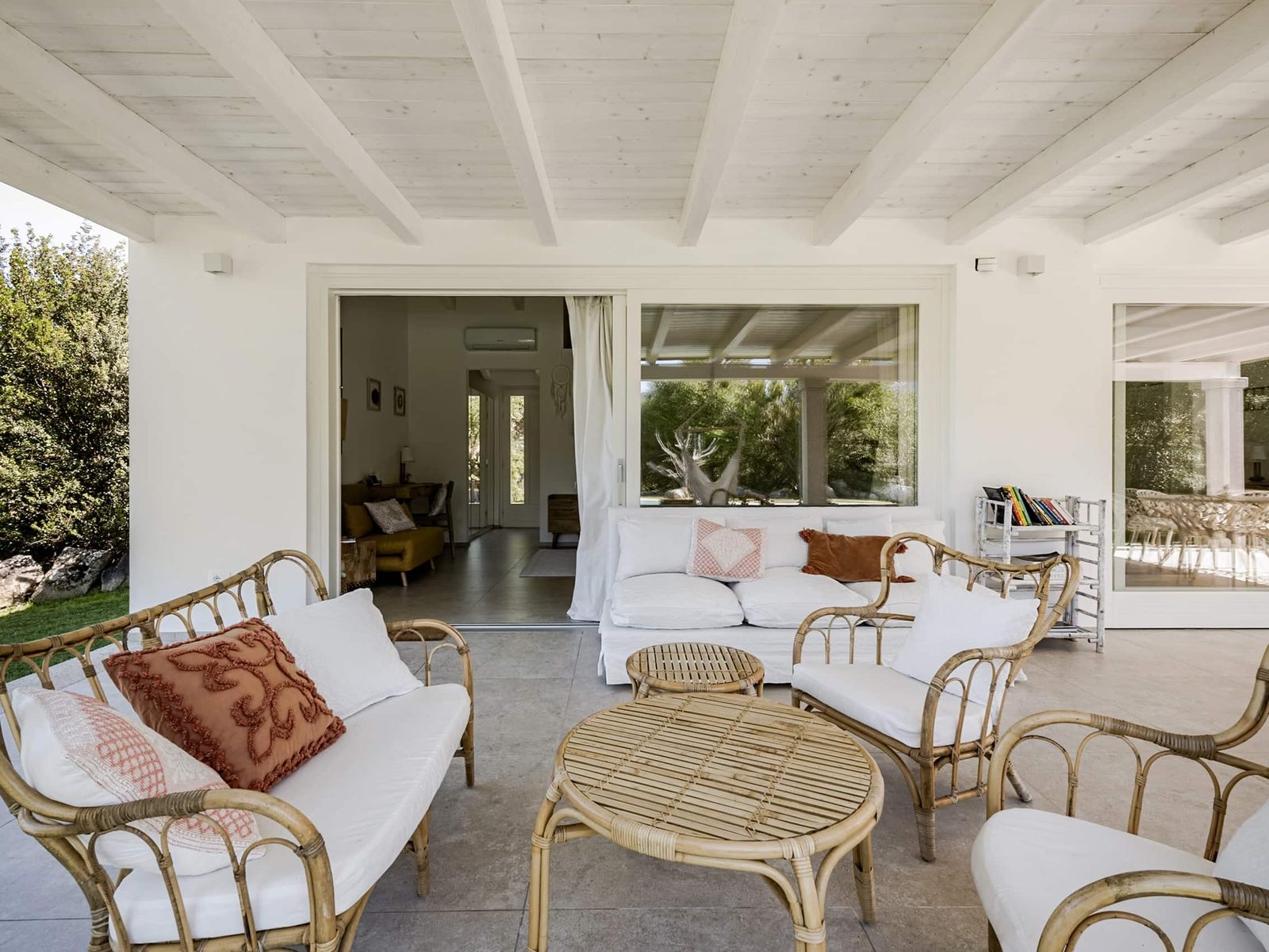 Il portico con il divano e le poltrone in rattan, aperto sul giardino