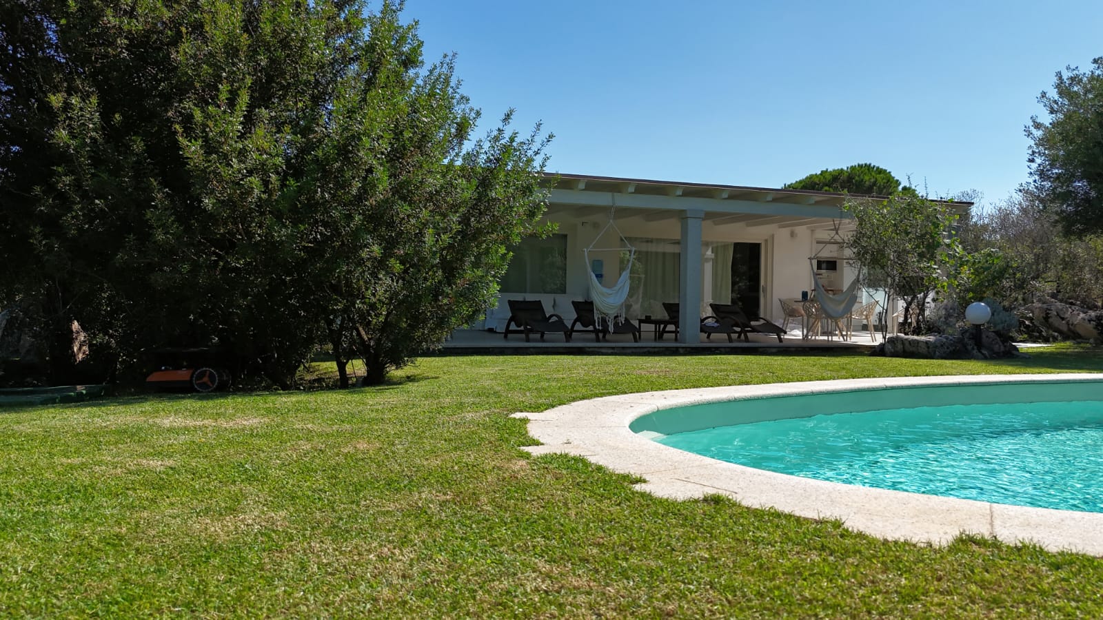 Il portico con i lettini e le amache oltre il prato, accanto alla piscina